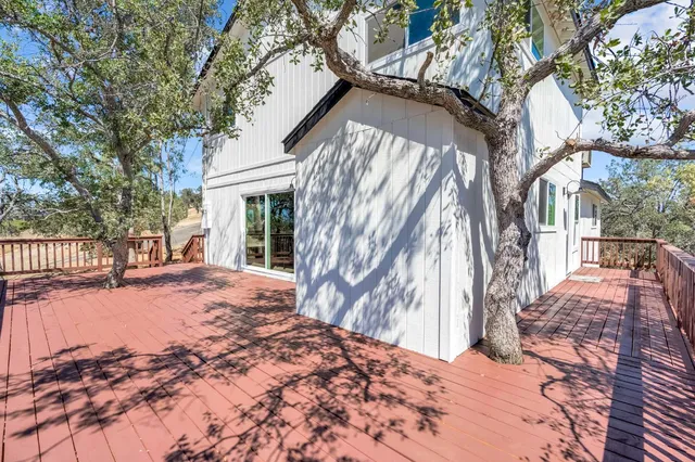a backyard of a house with large trees and wooden fence