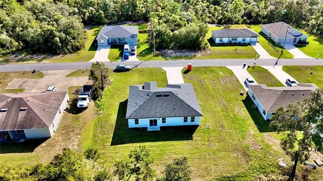 an aerial view of a house with swimming pool and large trees
