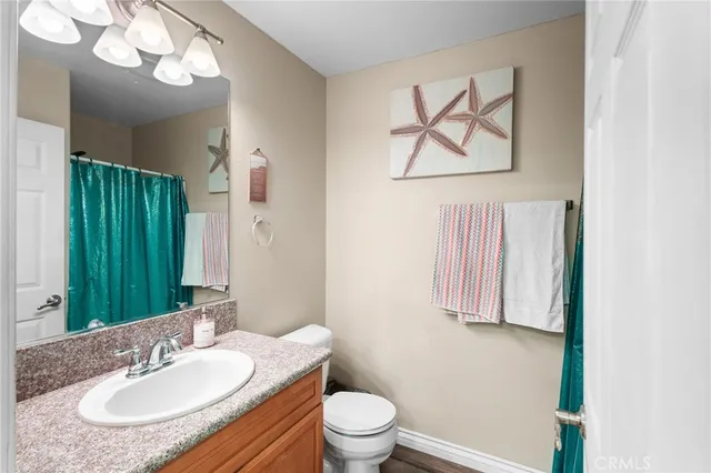a bathroom with a granite countertop sink a toilet and a mirror