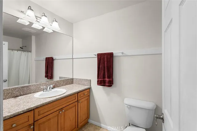 a bathroom with a granite countertop sink toilet and mirror
