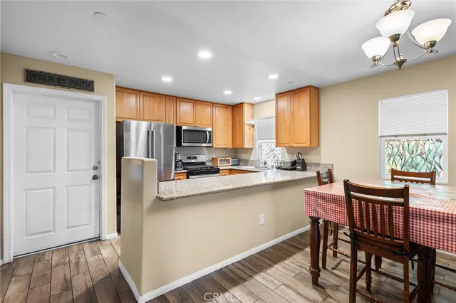 a kitchen with stainless steel appliances a dining table chairs a refrigerator and cabinets