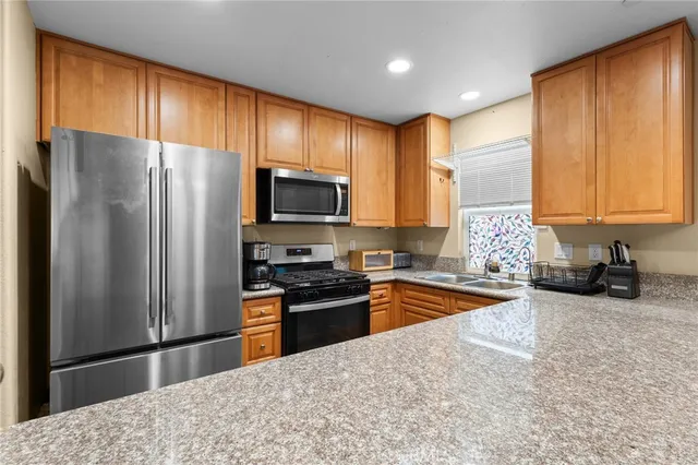 a kitchen with granite countertop a refrigerator stove and sink