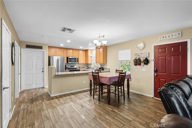 a kitchen with stainless steel appliances granite countertop a stove top oven a refrigerator a dining table and chairs with wooden floor