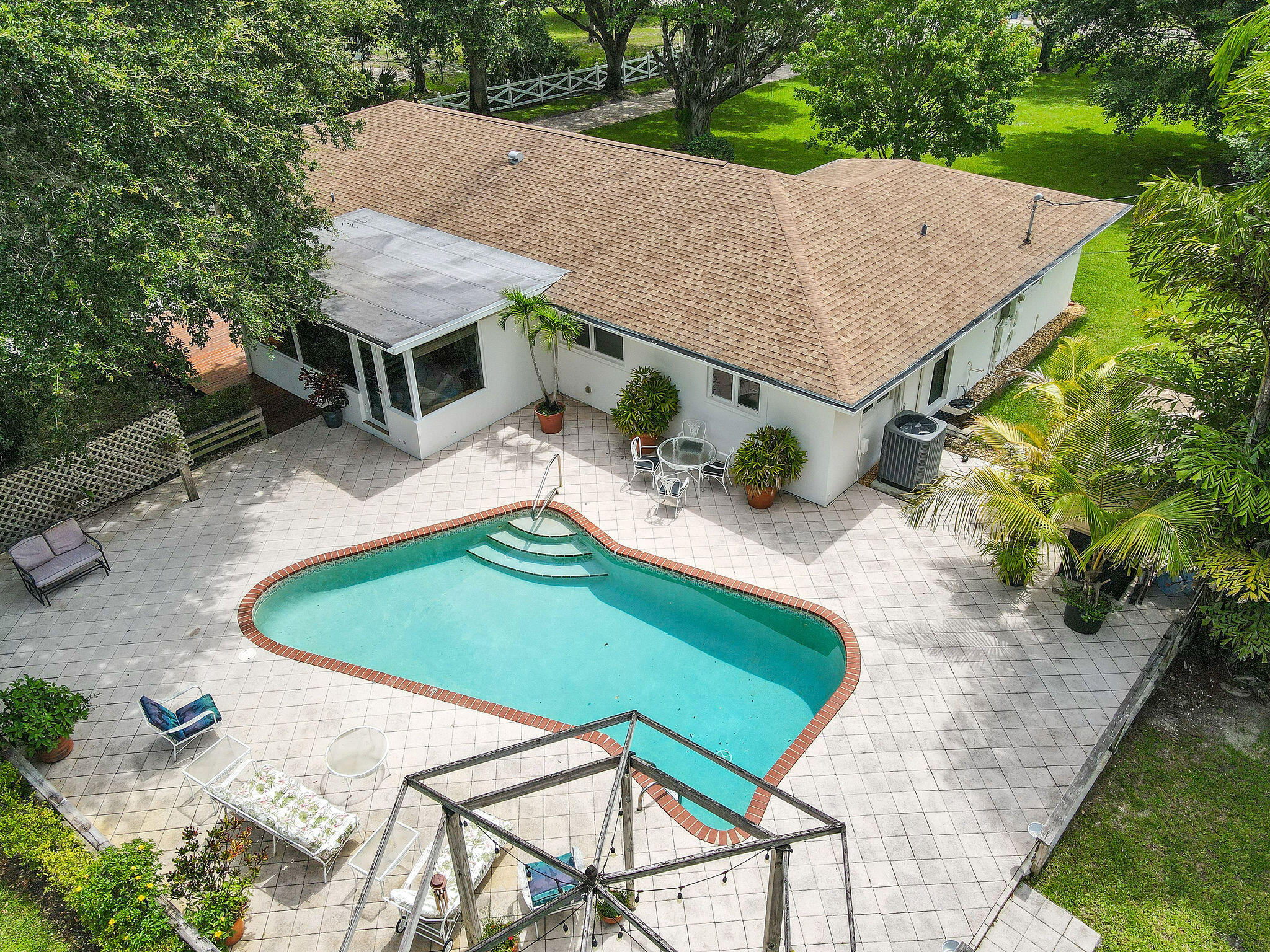 an aerial view of a house having patio yard swimming pool and red chairs