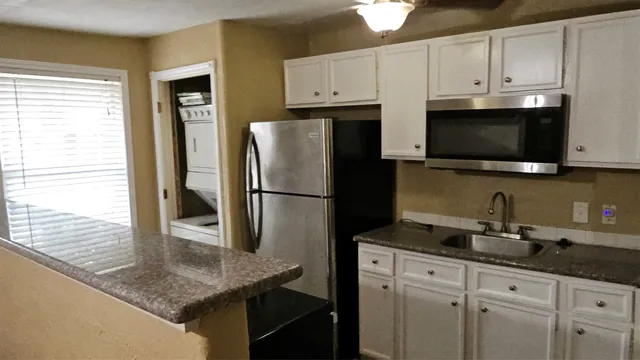 a kitchen with stainless steel appliances granite countertop a refrigerator a stove a sink and white cabinets