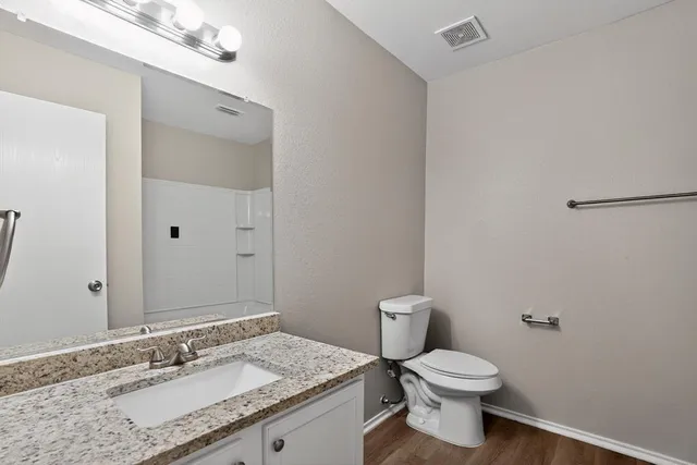 a bathroom with a granite countertop sink a toilet and a mirror