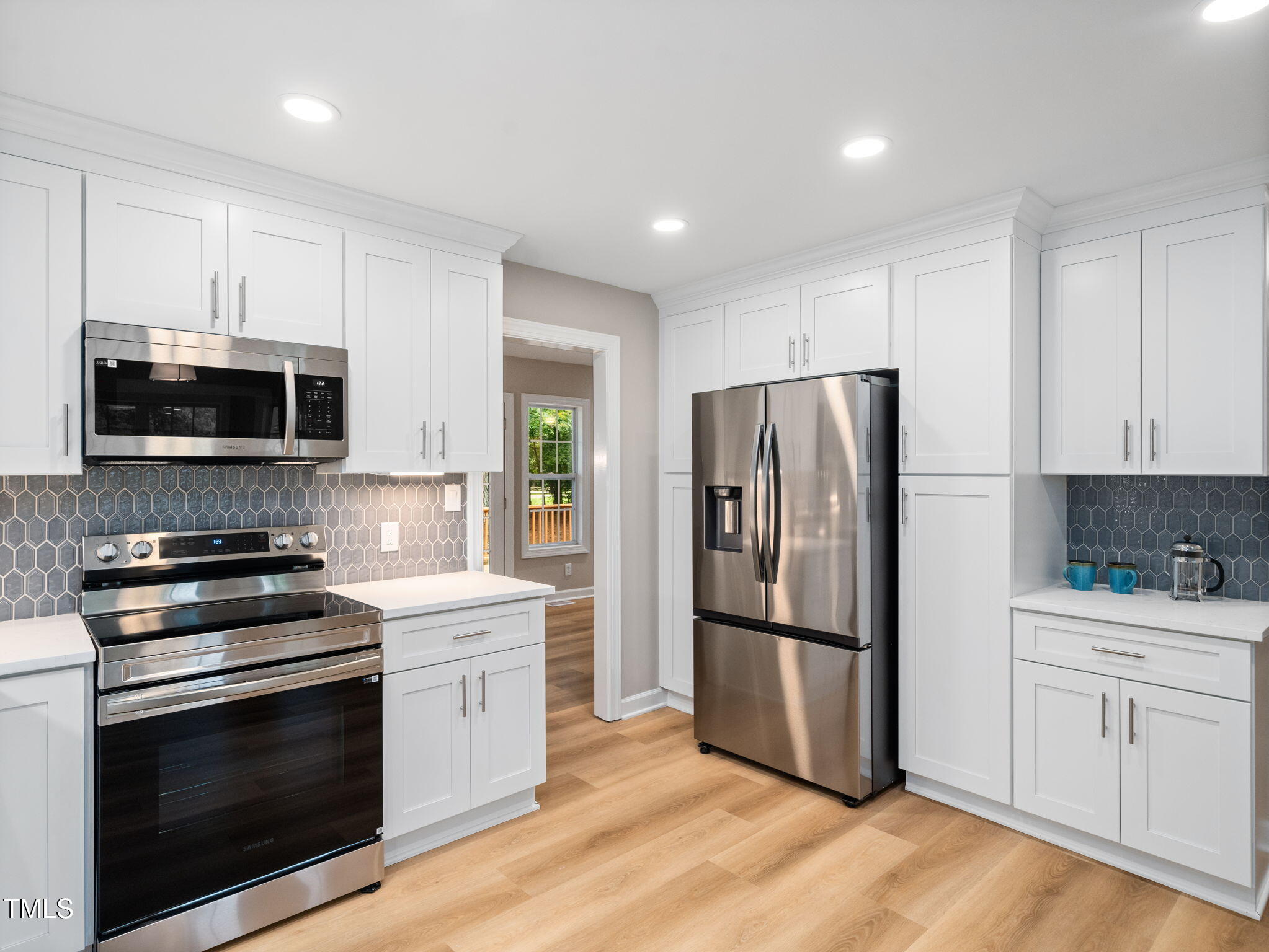 4700 Carolton Drive Raleigh, NC 27606 - Photo 9 of 29 a kitchen with white cabinets stainless steel appliances and wooden floors