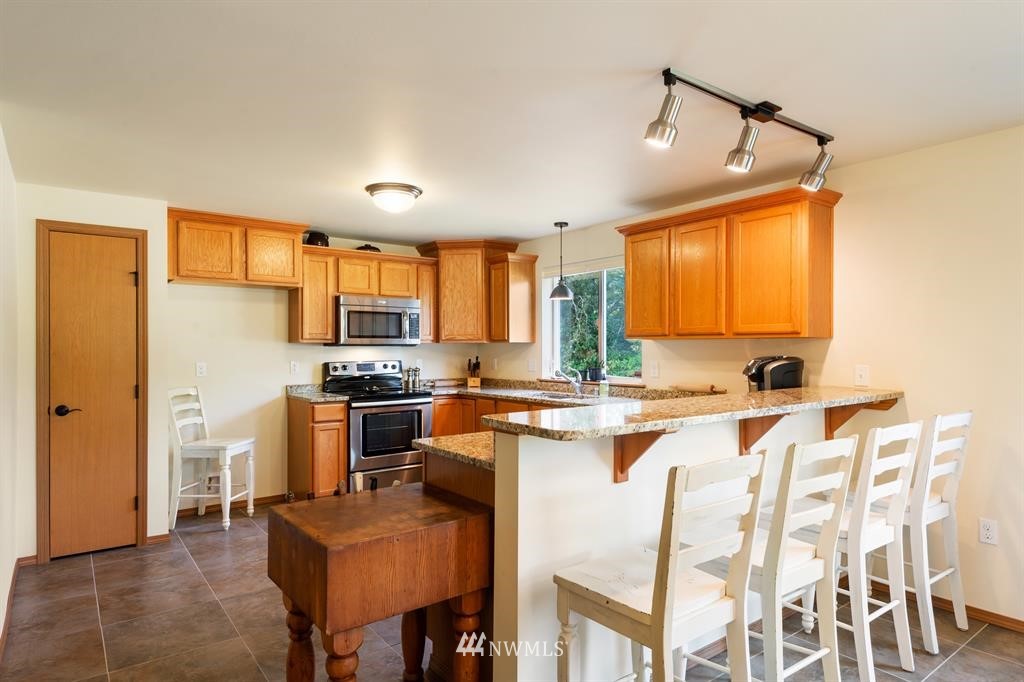 712 Bergeson Road Southwest Lakebay, WA 98349 - Photo 22 of 36 a kitchen with a refrigerator a stove top oven a sink dishwasher and white cabinets with wooden floor