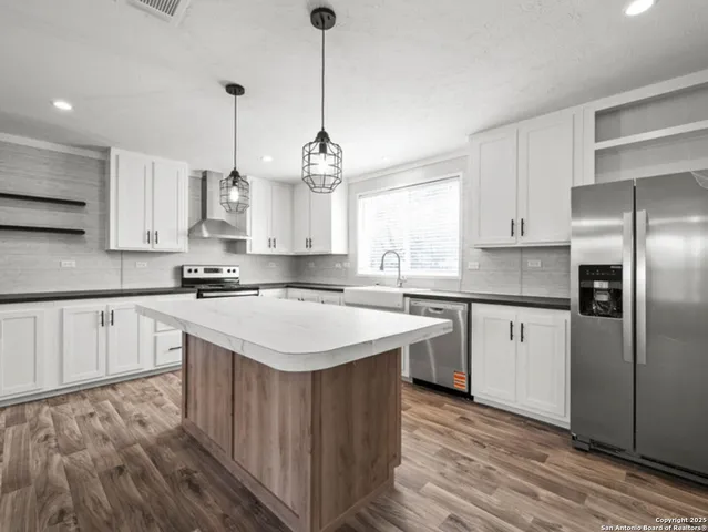 a kitchen with kitchen island a stove a sink a center island and wooden floor