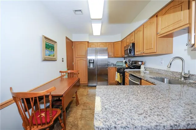 a kitchen with stainless steel appliances granite countertop a sink a stove and island