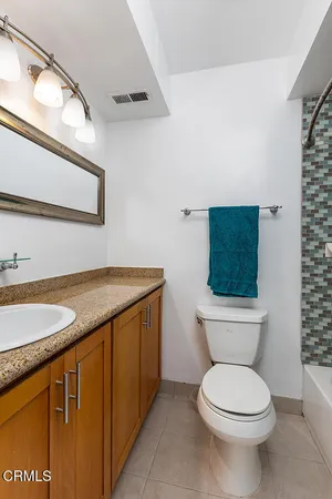 a bathroom with a granite countertop toilet sink and mirror