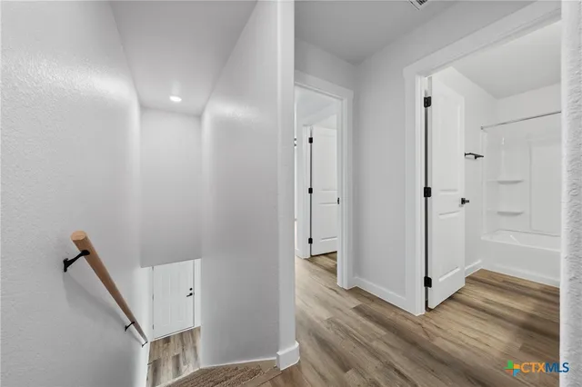 a view of a hallway with closet and wooden floor