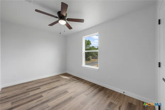 an empty room with ceiling fan and window