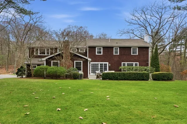 a view of a house with a big yard and potted plants and large trees