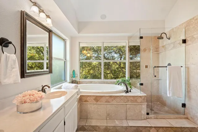 a bathroom with a granite countertop tub sink and large window