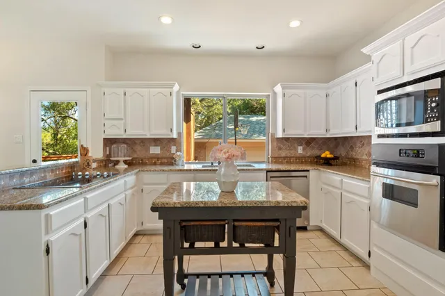 a kitchen with a stove a sink and white cabinets
