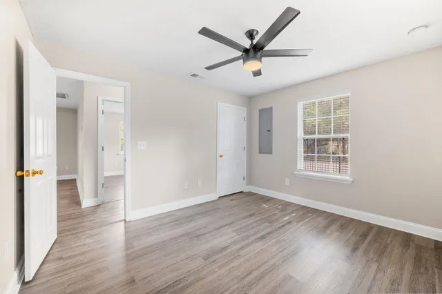 an empty room with wooden floor and windows