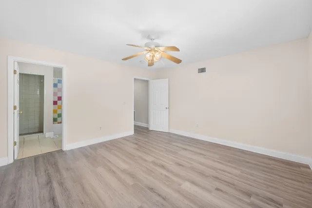 a view of a room with wooden floor and a ceiling fan