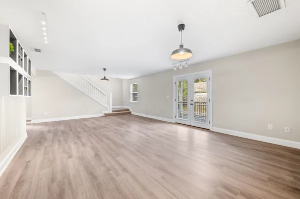 an empty room with wooden floor ceiling fan and windows