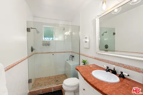 a bathroom with a granite countertop sink a toilet a mirror and shower