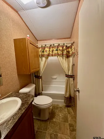 a bathroom with a granite countertop sink toilet and a mirror