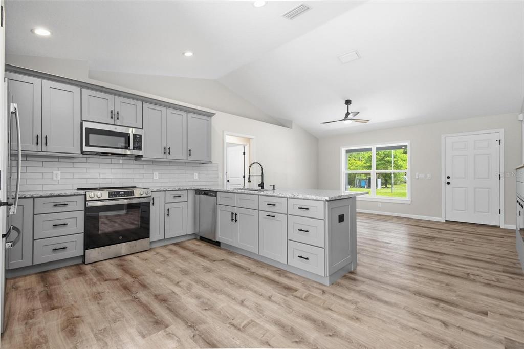1730 Berrybush Street Bunnell, FL 32110 - Photo 12 of 43 a kitchen with stainless steel appliances a stove top oven a sink a window and white cabinets
