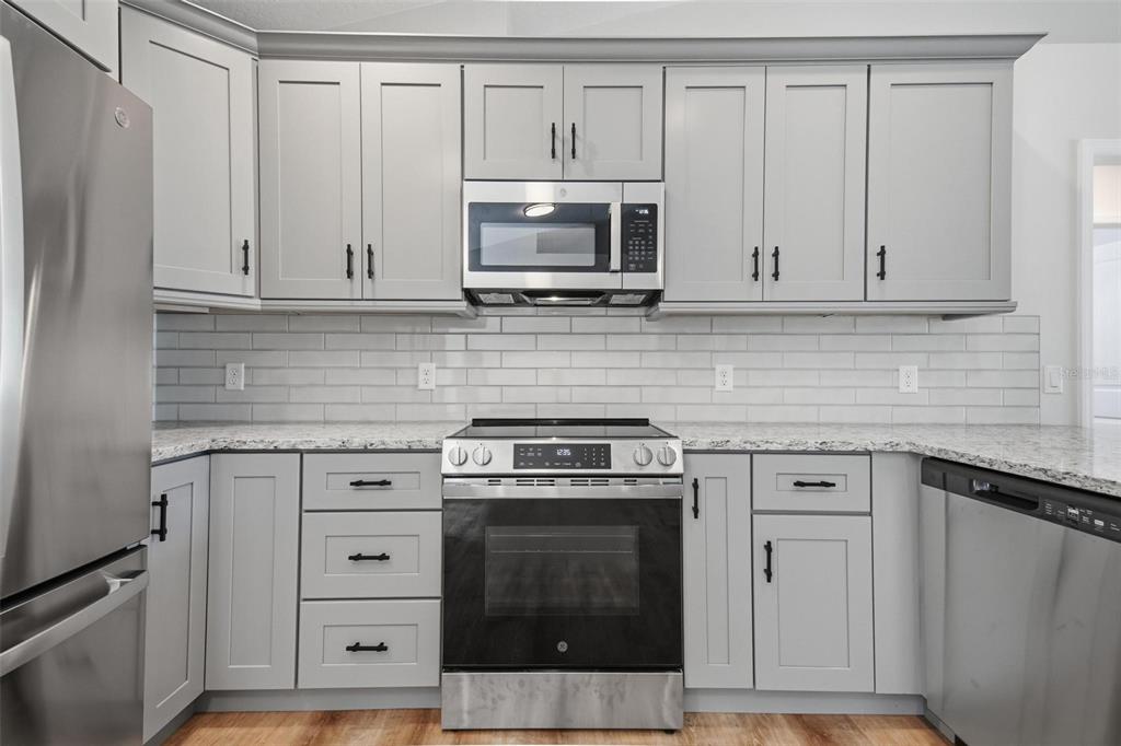 1730 Berrybush Street Bunnell, FL 32110 - Photo 13 of 43 a kitchen with white cabinets and stainless steel appliances