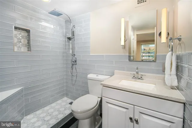 a bathroom with a granite countertop toilet sink and mirror