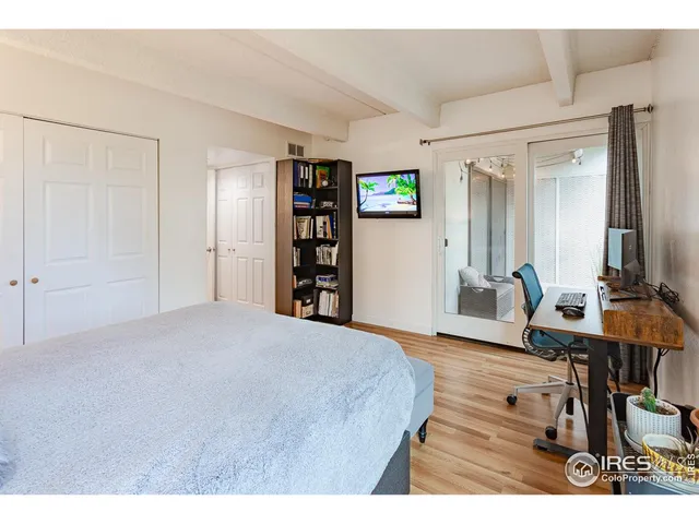 a bedroom with a bed a computer on the desk and a book shelf