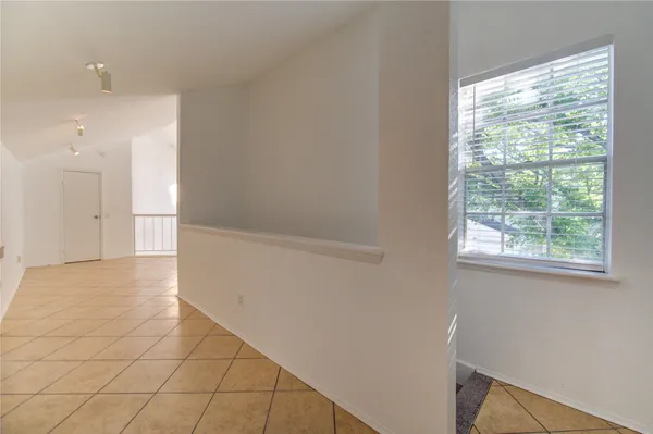 a view of an empty room with wooden floor and a ceiling fan
