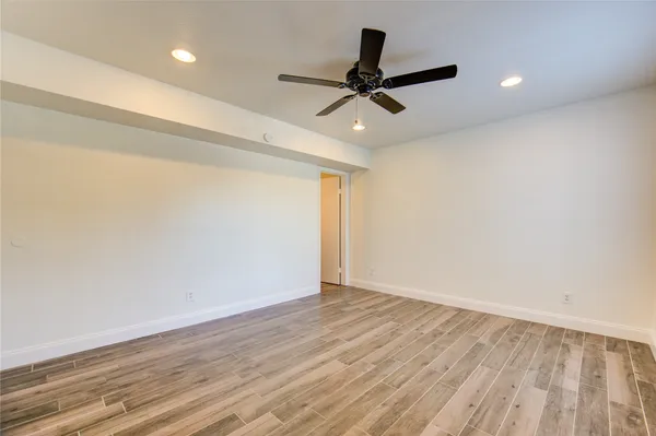 a view of empty room with wooden floor and fan