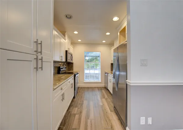 a kitchen with kitchen island wooden floors appliances and cabinets
