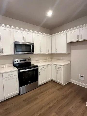 a kitchen with granite countertop white cabinets and stainless steel appliances