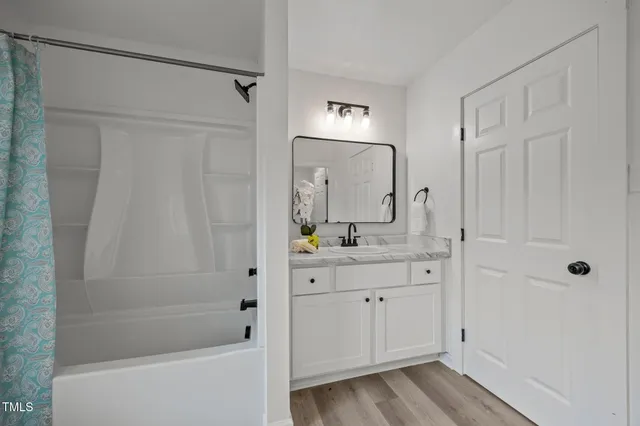 a bathroom with a granite countertop sink a mirror a vanity and a bathtub