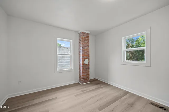 an empty room with wooden floor and window