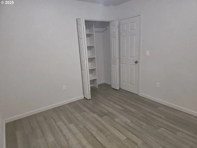 a view of an empty room with wooden floor and closet
