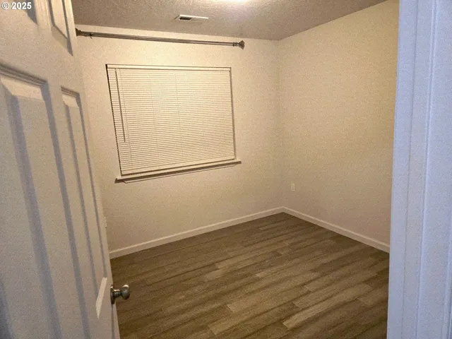 an empty room with wooden floor and mirror