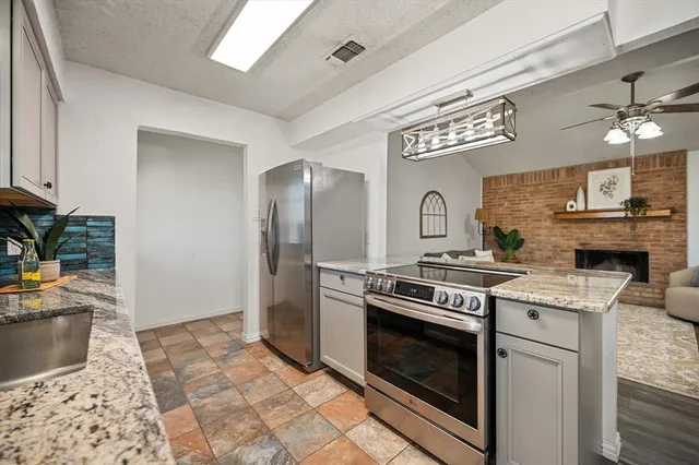 a kitchen with stainless steel appliances granite countertop a stove a sink and a refrigerator