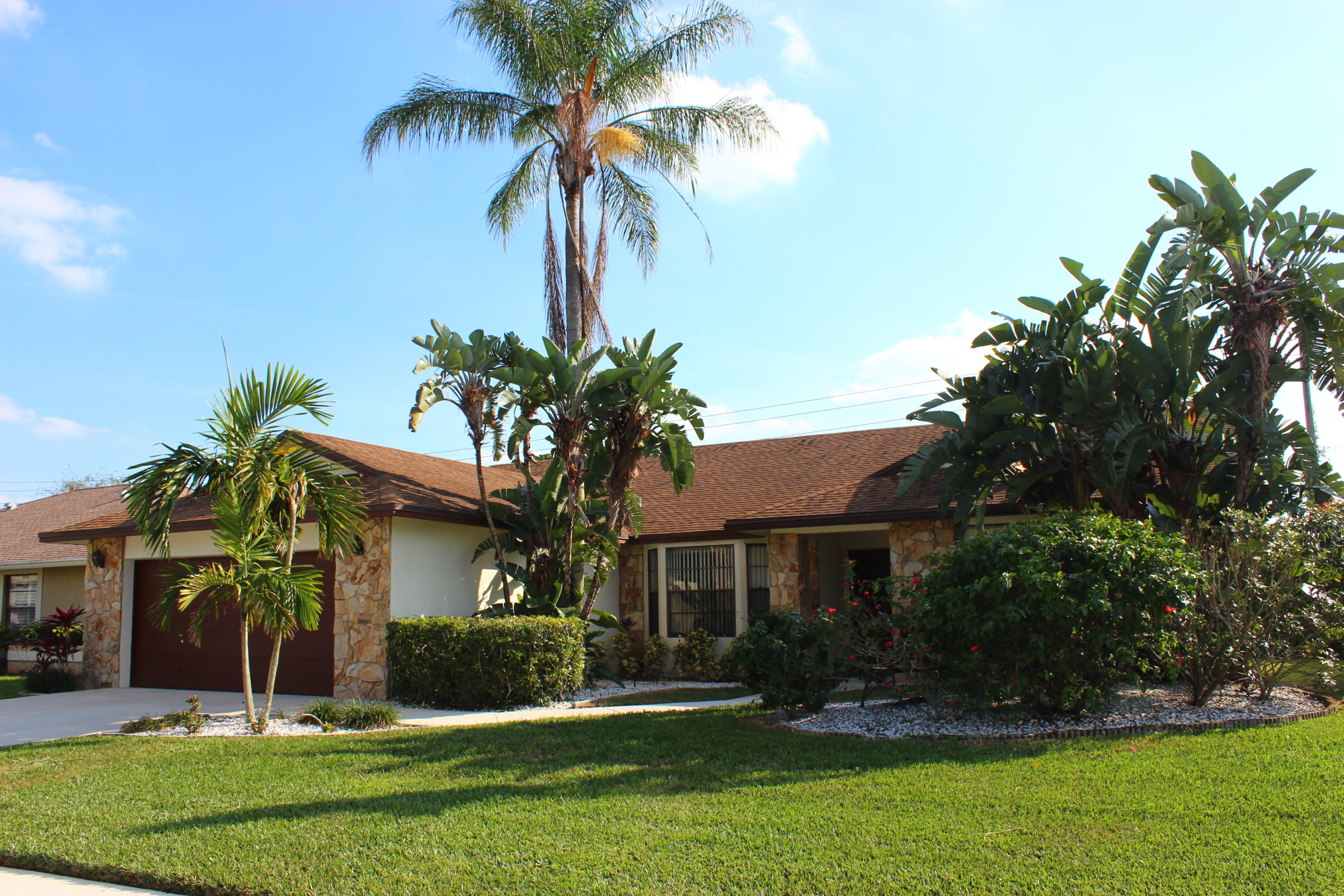 front view of a house with a yard and palm trees