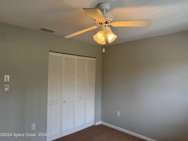 a view of a room with a chandelier fan and wooden floor