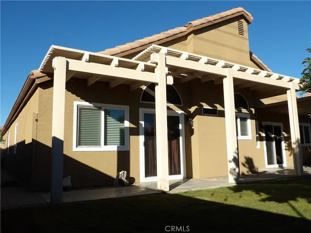 a view of a backyard with table and chairs plants and a barbeque