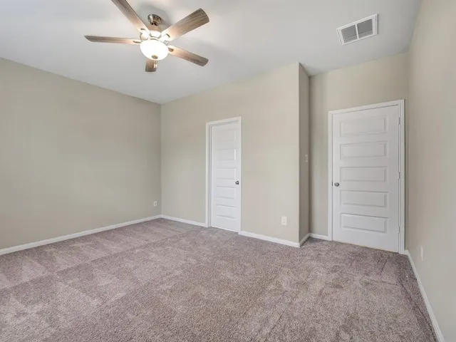 an empty room with closet and a ceiling fan