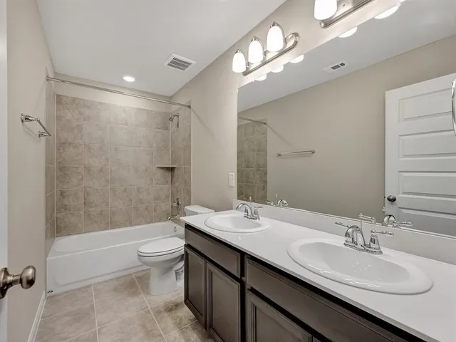 a bathroom with a double vanity sink toilet mirror and shower