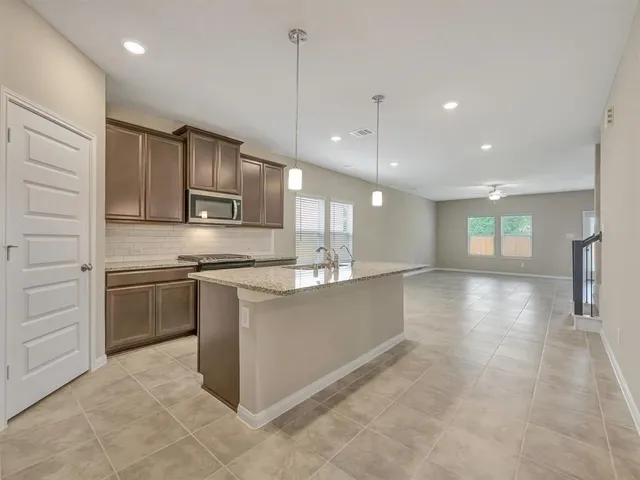 a large kitchen with stainless steel appliances kitchen island granite countertop a stove a sink and a refrigerator