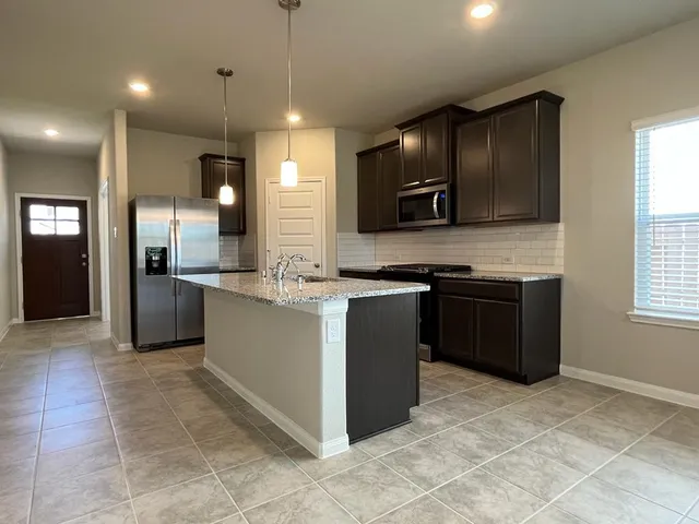 a kitchen with stainless steel appliances granite countertop a stove a refrigerator and a sink