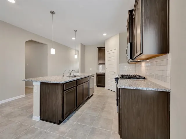 a large kitchen with kitchen island a sink dishwasher a stove a refrigerator and a oven with wooden cabinets