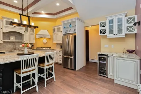 a kitchen with stainless steel appliances kitchen island granite countertop a table chairs and a refrigerator