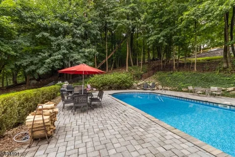 a view of a swimming pool with a table and chairs under an umbrella