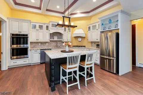 a kitchen with stainless steel appliances a dining table chairs stove and refrigerator