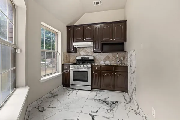 a kitchen with stainless steel appliances granite countertop a stove and a refrigerator